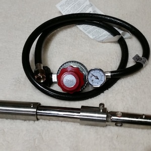 May include: A silver torch with a red knob and a pressure gauge, connected to a black hose and a regulator with a 30 PSI label.