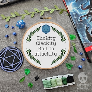 May include: A white embroidery hoop with a blue and green cross-stitch design. The design features a blue 20-sided die and the text "Clickity Clackity Roll to Attackity".