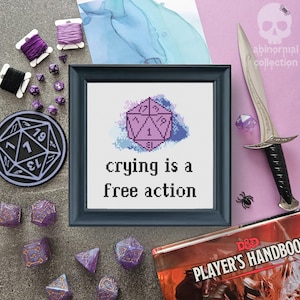 Puede incluir: Un patrón de punto de cruz con un dado de estilo acuarela morado y azul con el texto "llorar es una acción libre".
