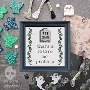 May include: A black framed cross-stitch with a tombstone and the text "that's a future me problem" surrounded by green ivy.