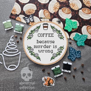 Puede incluir: Un aro de bordado de punto de cruz con fondo blanco y bordado verde y negro. El bordado dice "COFFEE because murder is wrong".