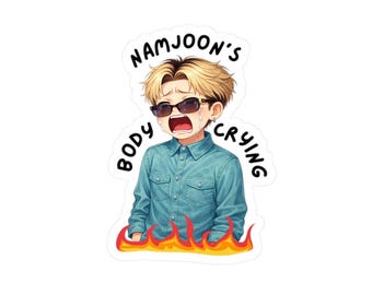 May include: A sticker featuring an anime-style illustration of a person with blonde hair and sunglasses, crying. The person wears a blue button-down shirt and is surrounded by flames. Text reads "NAMJOON'S BODY CRYING."