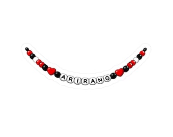 May include: A sticker featuring a beaded necklace design. The necklace has red, black, and white beads, with heart-shaped beads. The word "ARIRANG" is spelled out in white letter beads.