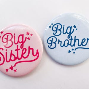 May include: Two round buttons with the words "Big Sister" and "Big Brother" in a retro font. The "Big Sister" button is pink with red text and the "Big Brother" button is blue with blue text. Both buttons have small white stars around the text.