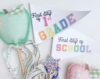 May include: Two pennant flags with rainbow letters. The first flag says "First day of 1st GRADE" and the second flag says "First day of SCHOOL".