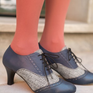 May include: A pair of blue and grey tweed heeled shoes with black laces. The shoes have a pointed toe and a small heel.