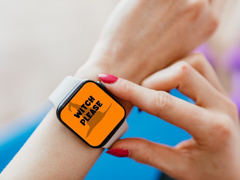 May include: A white smartwatch with a black screen displaying the text "WITCH PLEASE" in white letters and a brown witch hat graphic on an orange background. The watch is on a wrist with red nail polish.