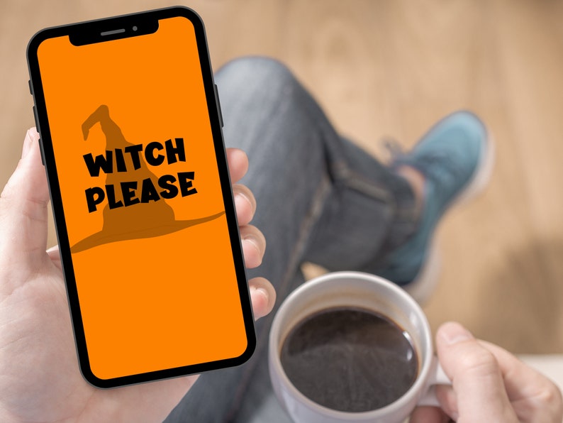 May include: A smartphone displays an orange screen with a witch hat silhouette and the words "WITCH PLEASE" in black. The phone is held in a hand, with a cup of coffee in the other hand. The theme is Halloween.