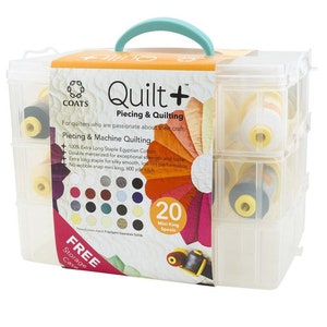 May include: A clear plastic storage case with a teal handle contains 20 mini king spools of Coats Quilt+ thread. The spools are arranged in a grid pattern. The box has a label that says "Quilt+ Piecing & Quilting" and "For quilters who are passionate about their craft." The label also includes a list of features, such as "100% Extra Long Staple Egyptian Cotton" and "No wobble snap mini king, 600 yd each".