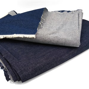 May include: Two pieces of denim fabric, one dark blue and one light blue, folded on a white surface.
