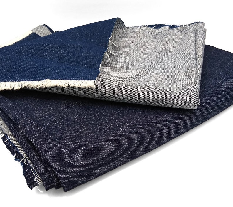 May include: Two pieces of denim fabric, one dark blue and one light blue, folded on a white surface.