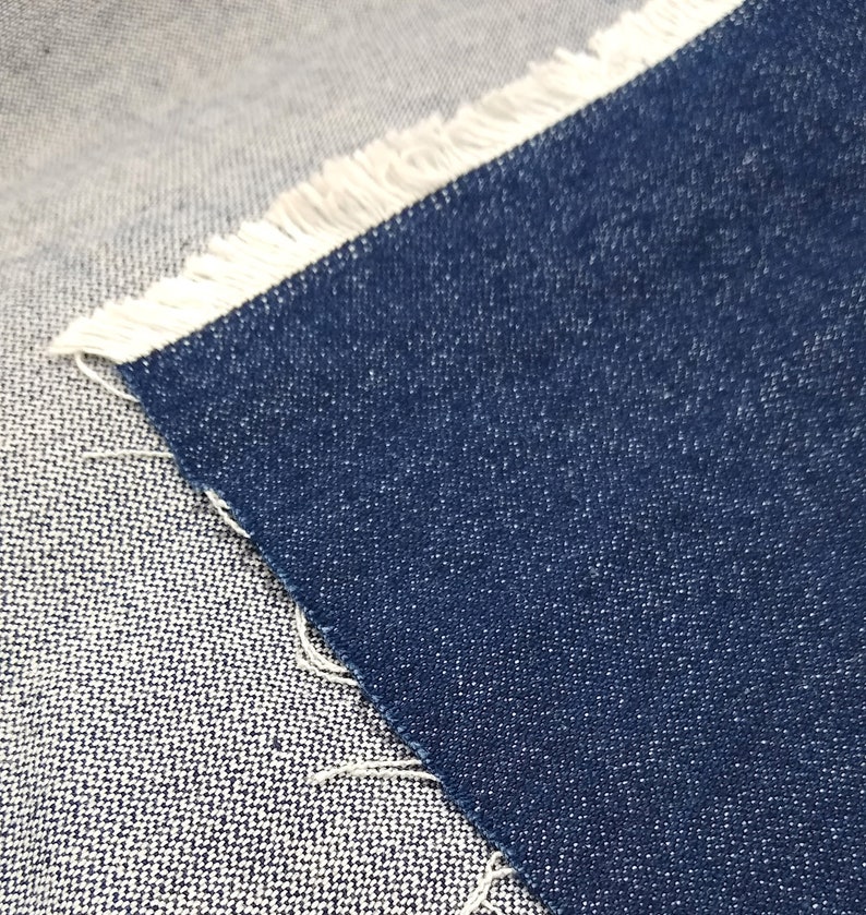 May include: Close-up of two different types of denim fabric. One is a light blue denim with a white fringe, and the other is a dark blue denim.