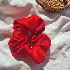 Puede incluir: Un scrunchie de satén rojo brillante para el cabello.