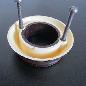 May include: A white plastic ring with a brown inner ring and two silver screws. The ring has a hole in the center.