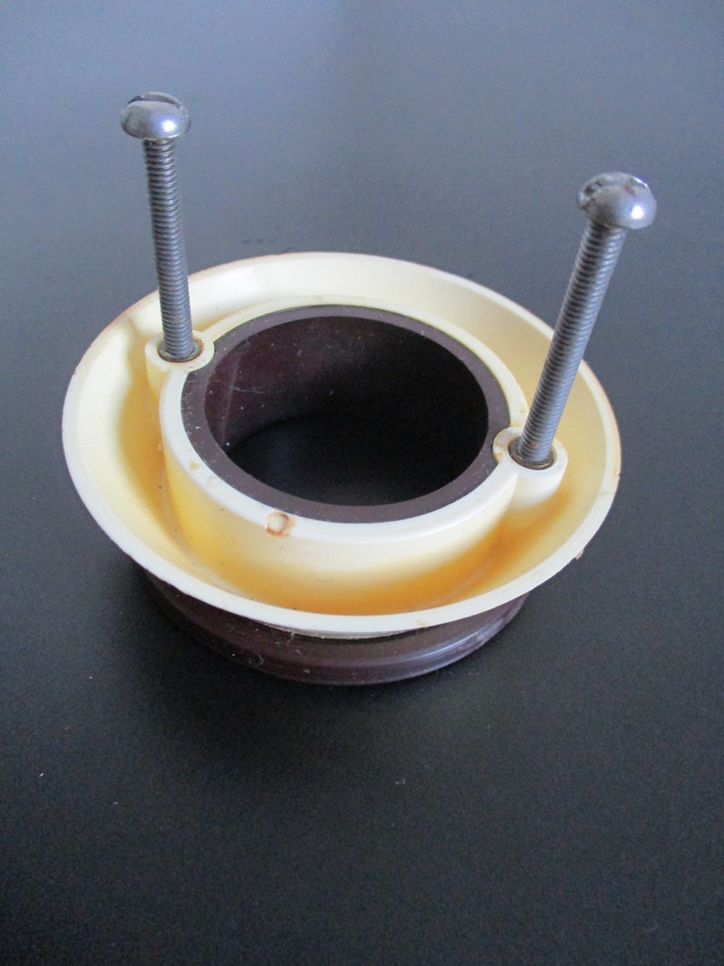 May include: A white plastic ring with a brown inner ring and two silver screws. The ring has a hole in the center.