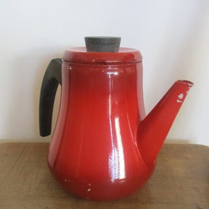 Op de afbeelding: Rode emaille koffiekan met een zwarte handgreep en een zwart deksel.