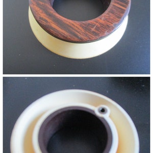 May include: A wooden ring with a brown and white pattern, with a smaller ring inside. The outer ring is made of wood and the inner ring is made of plastic.