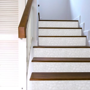 May include: White tile stair treads with a wood base. The tiles are a light white with a subtle texture. The wood is a dark brown.