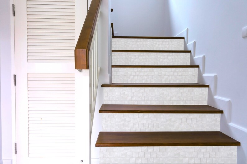 May include: White tile stair treads with a wood base. The tiles are a light white with a subtle texture. The wood is a dark brown.