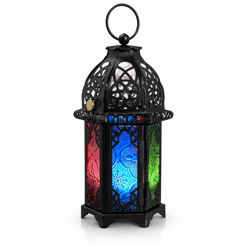 May include: A black metal lantern featuring a domed top with a circular hanging ring. The lantern has six sides with intricate cut-out patterns and panels of textured glass in vibrant red, blue, and green colors. A small gold-colored latch is visible.