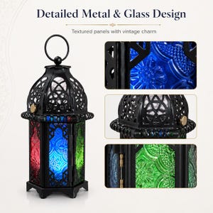 May include: A black metal lantern featuring a circular top handle and six-sided frame with textured glass panels in red, blue, and green. The lantern includes intricate cut-out patterns on the metal dome and a hinged door with a small latch.