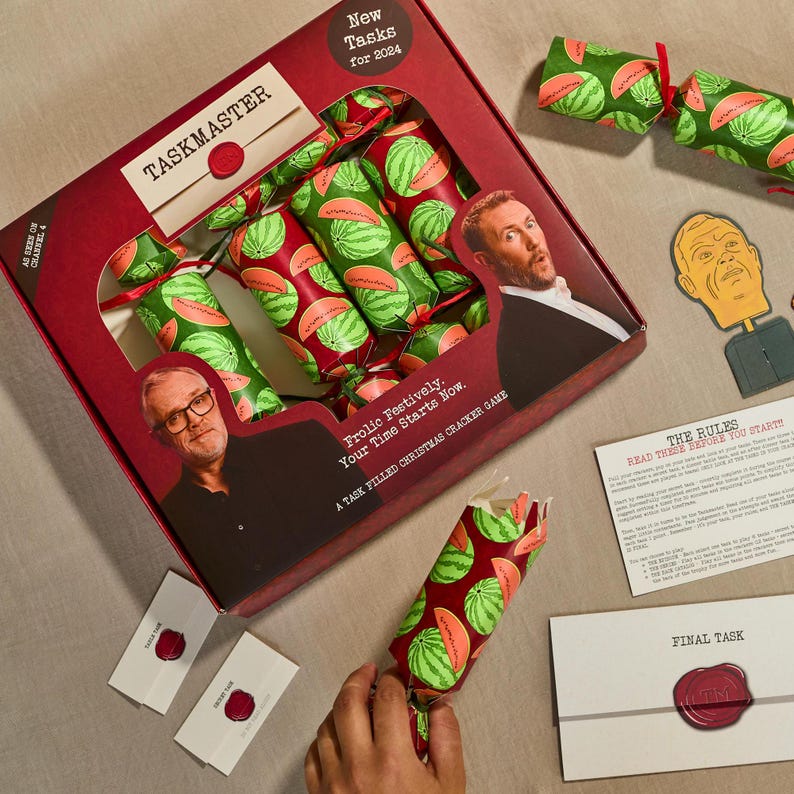 May include: A set of Taskmaster Christmas crackers with a watermelon pattern. The box features the show's logo and the text "New Tasks for 2024".
