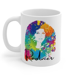 May include: White ceramic mug featuring a colorful portrait of a woman with a vibrant, abstract design. The portrait is surrounded by a splash of rainbow colors, with the name "Radner" in black script below the portrait.