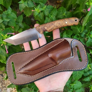 May include: A brown leather sheath with a stitched design and a single belt loop. A knife with a wooden handle and a silver blade is in the sheath.