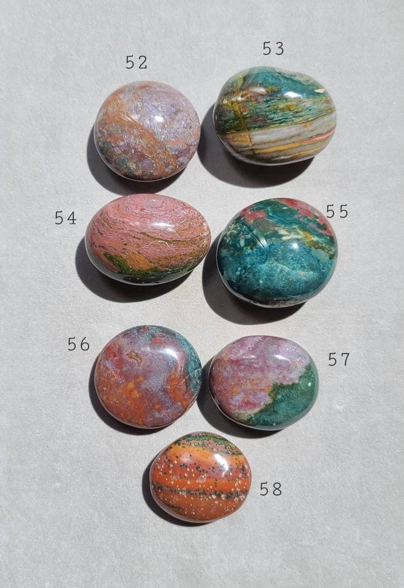 Pu&ograve; includere: Sette pietre lisce e levigate con vari motivi di verde, rosa, arancio e marrone. Le pietre sono numerate da 52 a 58.