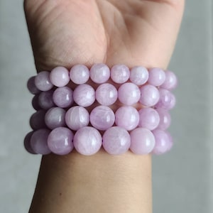 Peut inclure: Un ensemble de quatre bracelets en pierres pr&eacute;cieuses de couleur lavande avec des perles rondes. Chaque bracelet est compos&eacute; de pierres lisses et polies.
