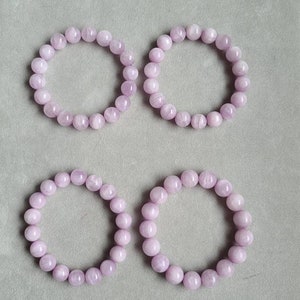 Peut inclure: Quatre bracelets en perles de pierres pr&eacute;cieuses de couleur lilas clair. Les perles sont rondes et mesurent de 10 &agrave; 11 mm de diam&egrave;tre.