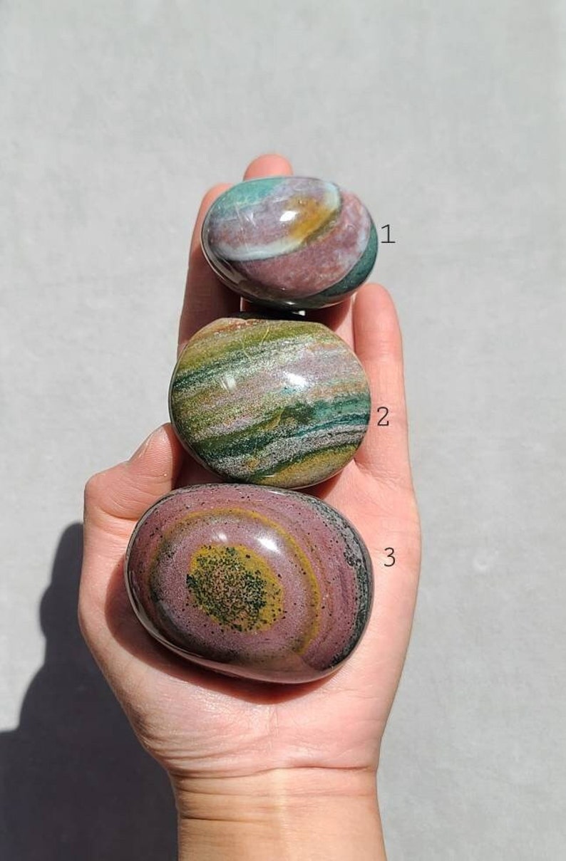 Pu&ograve; includere: Tre pietre levigate con motivi a spirale verde, rosa e marrone. Le pietre sono numerate 1, 2 e 3.