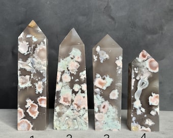 May include: Four polished agate obelisks with varying patterns of gray, pink, and white. Each obelisk has a pointed top and a rectangular base. The stones are numbered 1 through 4.