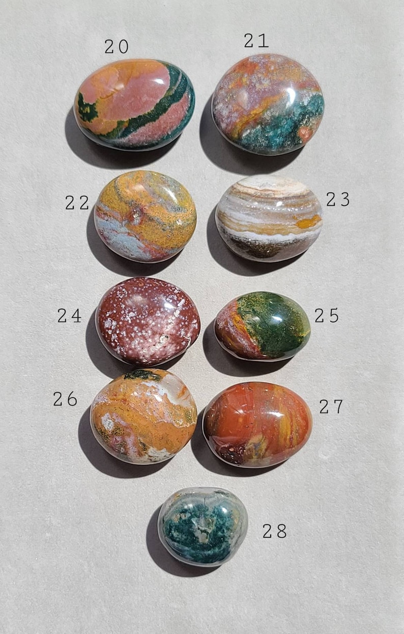 Pu&ograve; includere: Una collezione di otto pietre levigate di forma ovale con vari motivi e colori, tra cui rosso, verde, marrone, bianco e giallo. Le pietre sono numerate da 20 a 28.