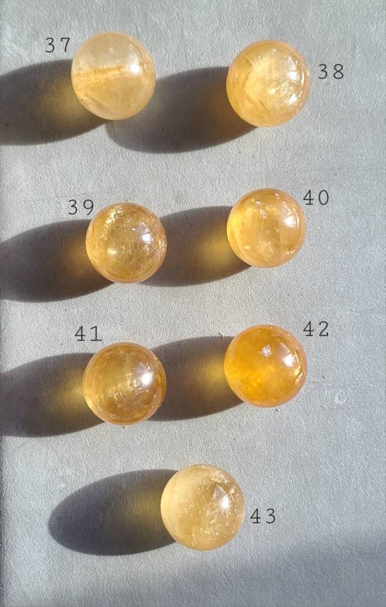 May include: Ten round, smooth, polished, yellow citrine spheres, numbered 37 through 43. The spheres are arranged in two rows of five, with the numbers written next to each sphere.