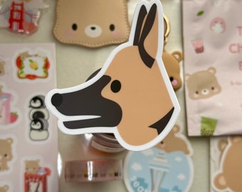 May include: A collection of stickers, keychains, and washi tape featuring cute bear and dog designs. The stickers include images of food, landmarks, and other bear-themed illustrations. The keychains are bear-shaped with gold-colored hardware.