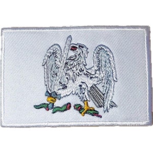 Puede incluir: Parche blanco bordado con un diseño de águila plateada. El águila sostiene una serpiente en sus garras y tiene un pico rojo y amarillo.