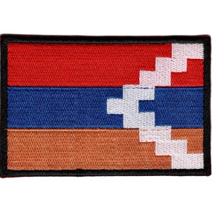 May include: Embroidered patch featuring the flag of Artsakh, a rectangular design with horizontal red, blue, and orange stripes. A white, jagged pattern is on the right side, outlined in black.