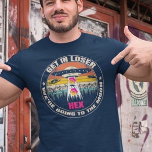 May include: A navy blue t-shirt with a retro-style graphic of a UFO and the text "Get in Loser, We're Going to the Moon" with the word "Hex" in the middle.