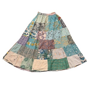 May include: A patchwork skirt made from various fabrics in shades of blue, green, and purple. The skirt has a gathered waist and a flowing silhouette.