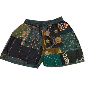 Puede incluir: Shorts de patchwork con un esquema de color verde, negro y marrón. Los shorts tienen una cintura con cordón y están hechos de una variedad de telas.