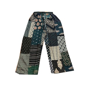 May include: Patchwork trousers in a mix of patterns and colours, including dark green, black, and cream. The trousers have a wide-leg design and are made from multiple fabric squares sewn together. The overall aesthetic is bohemian and unique.