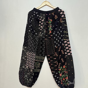 May include: Black trousers with a patchwork design featuring various floral and geometric patterns in shades of pink, white, and black.