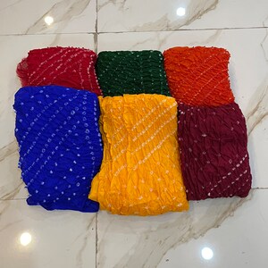 Peut inclure: Six carr&eacute;s de tissu color&eacute;s avec un motif tie-dye. Les carr&eacute;s sont dispos&eacute;s en deux rang&eacute;es de trois. Les couleurs sont rouge, vert, orange, bleu, jaune et marron.