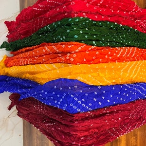 Peut inclure: Une pile de six &eacute;charpes color&eacute;es avec un motif tie-dye. Les &eacute;charpes sont rouge, verte, orange, jaune, bleue et marron.