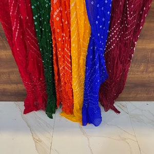 Peut inclure: Une collection de six foulards color&eacute;s avec un motif tie-dye et des points blancs. Les foulards sont dispos&eacute;s en rang&eacute;e, avec le foulard rouge &agrave; gauche et le foulard marron &agrave; droite. Les foulards sont faits d'un tissu doux et l&eacute;ger.