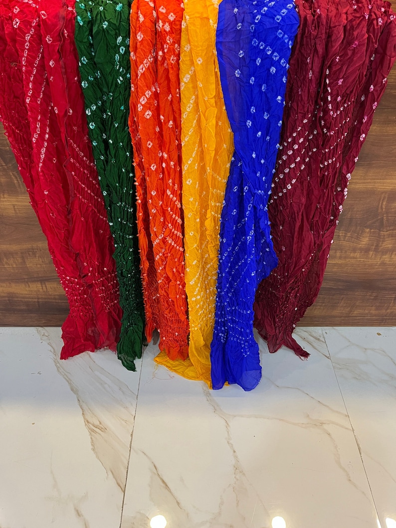 Peut inclure: Un ensemble de six foulards color&eacute;s avec un motif tie-dye. Les foulards sont dispos&eacute;s en rang&eacute;e, le foulard rouge &agrave; gauche et le foulard marron &agrave; droite. Les foulards sont faits d'un tissu doux et l&eacute;ger.