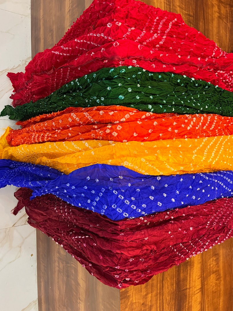 Peut inclure: Une pile de six &eacute;charpes color&eacute;es avec un motif tie-dye. Les &eacute;charpes sont dans des tons de rouge, vert, orange, jaune, bleu et marron.