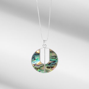 May include: A silver chain necklace with a round pendant featuring a green, blue, and purple abalone shell design.