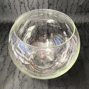 Peut inclure: Un grand bol rond en verre transparent. Le verre clair permet de voir l'intérieur. La forme du bol est sphérique, adapté à des fins décoratives ou fonctionnelles. Le diamètre du bol est d'environ 30 cm.